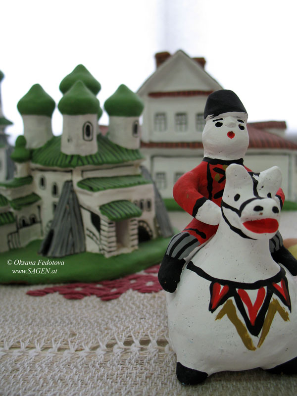 Mann auf dem Roß (Lippenpfeife). Im Hintergrund – der Kargopoler Dom-zur-Christi-Geburt. Museum des Kargopoler Spielzeuges im Zentrum der Volkshandwerke „Bereginja“. Kargopol © Oksana Fedotova 